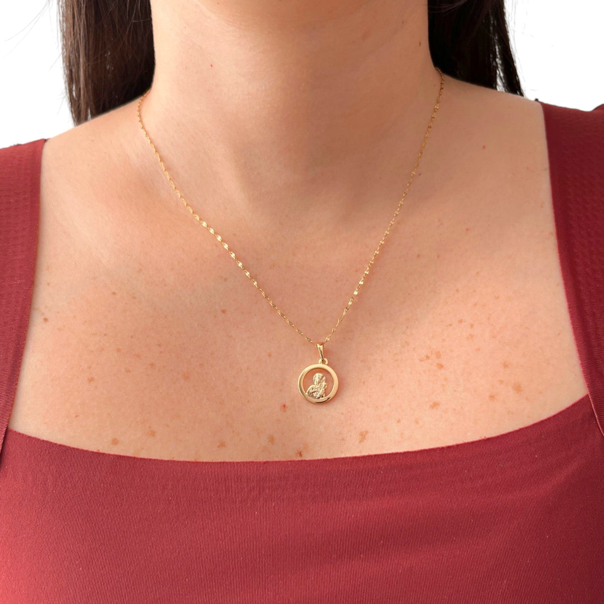 Cadena de tejido Espejo en acabado dorado, caracterizada por sus eslabones planos y pulidos que reflejan la luz intensamente. Lleva un dije de medalla circular calada en cuyo centro se aprecia la figura en relieve de la Virgen del Carmen.