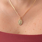 Cadena de tejido Grumet en acabado dorado, acompañada por un dije en forma de medalla ovalada. En el centro destaca la imagen en relieve de San Judas Tadeo sobre un fondo texturizado, enmarcada por un borde de perfil liso.