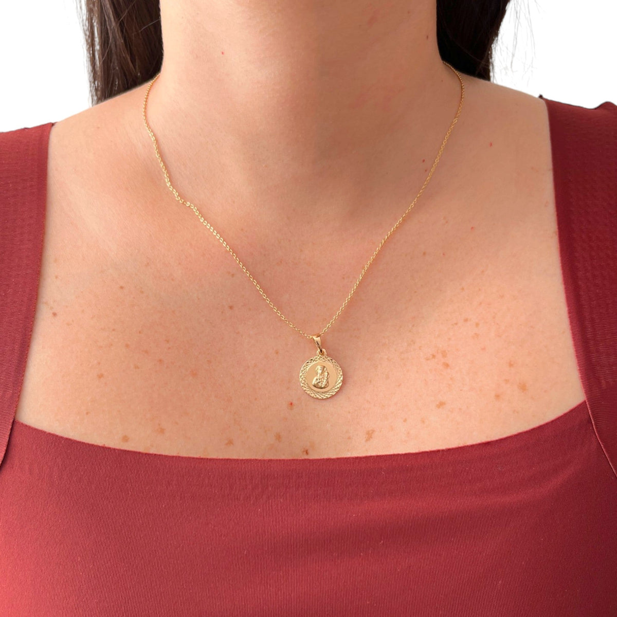 Cadena de tejido Rolo en acabado dorado, acompañada por un dije en forma de medalla circular. En el centro se distingue la figura en relieve de la Virgen del Carmen con el Niño Jesús, enmarcada por un llamativo borde con tallado diamantado o labrado que aporta un brillo especial a la pieza.