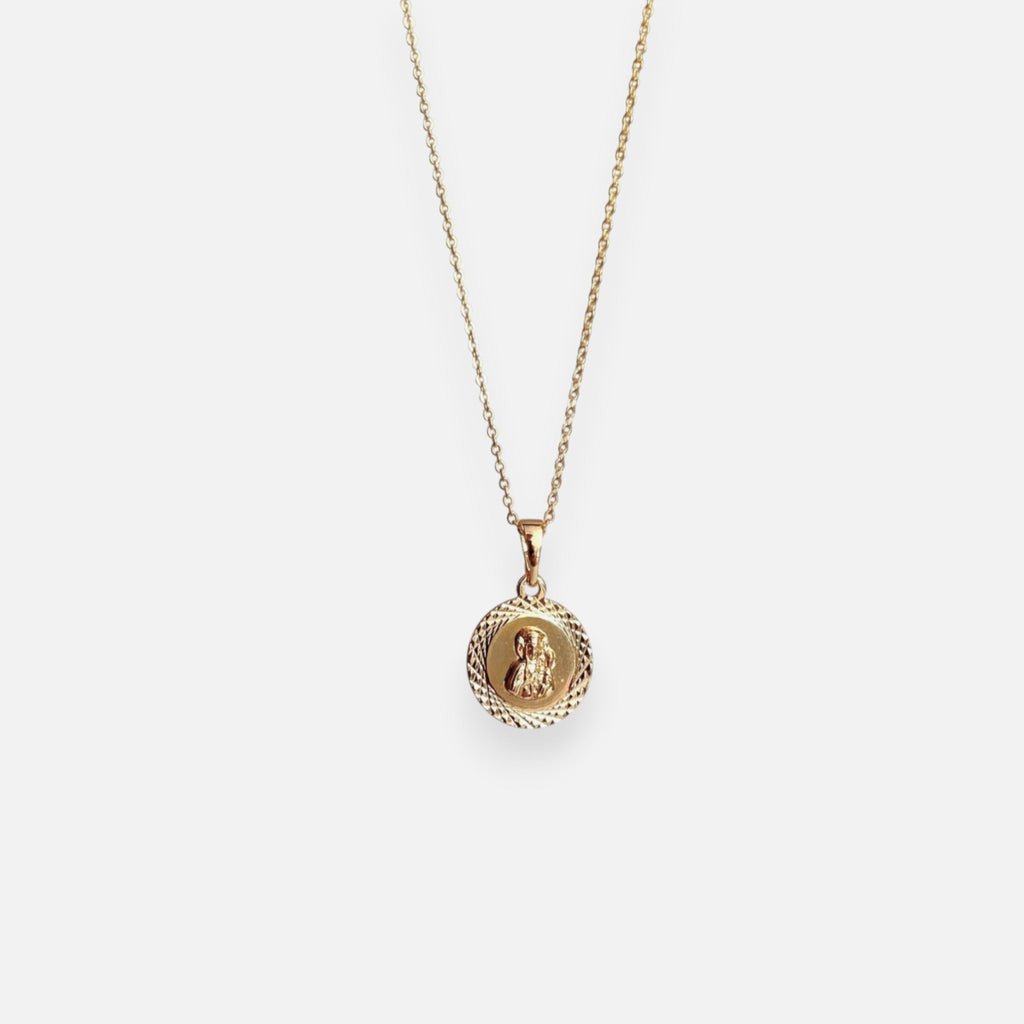 Cadena de tejido Rolo en acabado dorado, acompañada por un dije en forma de medalla circular. En el centro se distingue la figura en relieve de la Virgen del Carmen con el Niño Jesús, enmarcada por un llamativo borde con tallado diamantado o labrado que aporta un brillo especial a la pieza.