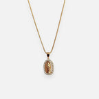 Cadena fina de tejido veneciana redondeada en acabado dorado, acompañada por un dije de medalla ovalada con la figura en relieve de la Virgen de Guadalupe. La pieza está enmarcada por un borde engastado con circonias brillantes.