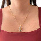 Cadena fina de tejido veneciana redondeada en acabado dorado, acompañada por un dije de medalla ovalada con la figura en relieve de la Virgen de Guadalupe. La pieza está enmarcada por un borde engastado con circonias brillantes.