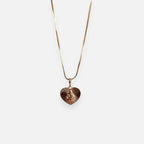Cadena de tejido Veneciana en acabado dorado, acompañada por un dije en forma de corazón doble cara o reversible. Por una cara presenta la imagen del Sagrado Corazón de Jesús con halo radiante y por la otra la figura de la Virgen del Carmen sobre un fondo texturizado de destellos. Una pieza versátil de gran devoción y protección.