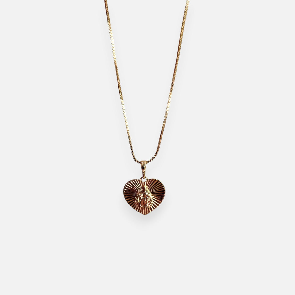 Cadena de tejido Veneciana en acabado dorado, acompañada por un dije en forma de corazón doble cara o reversible. Por una cara presenta la imagen del Sagrado Corazón de Jesús con halo radiante y por la otra la figura de la Virgen del Carmen sobre un fondo texturizado de destellos. Una pieza versátil de gran devoción y protección.