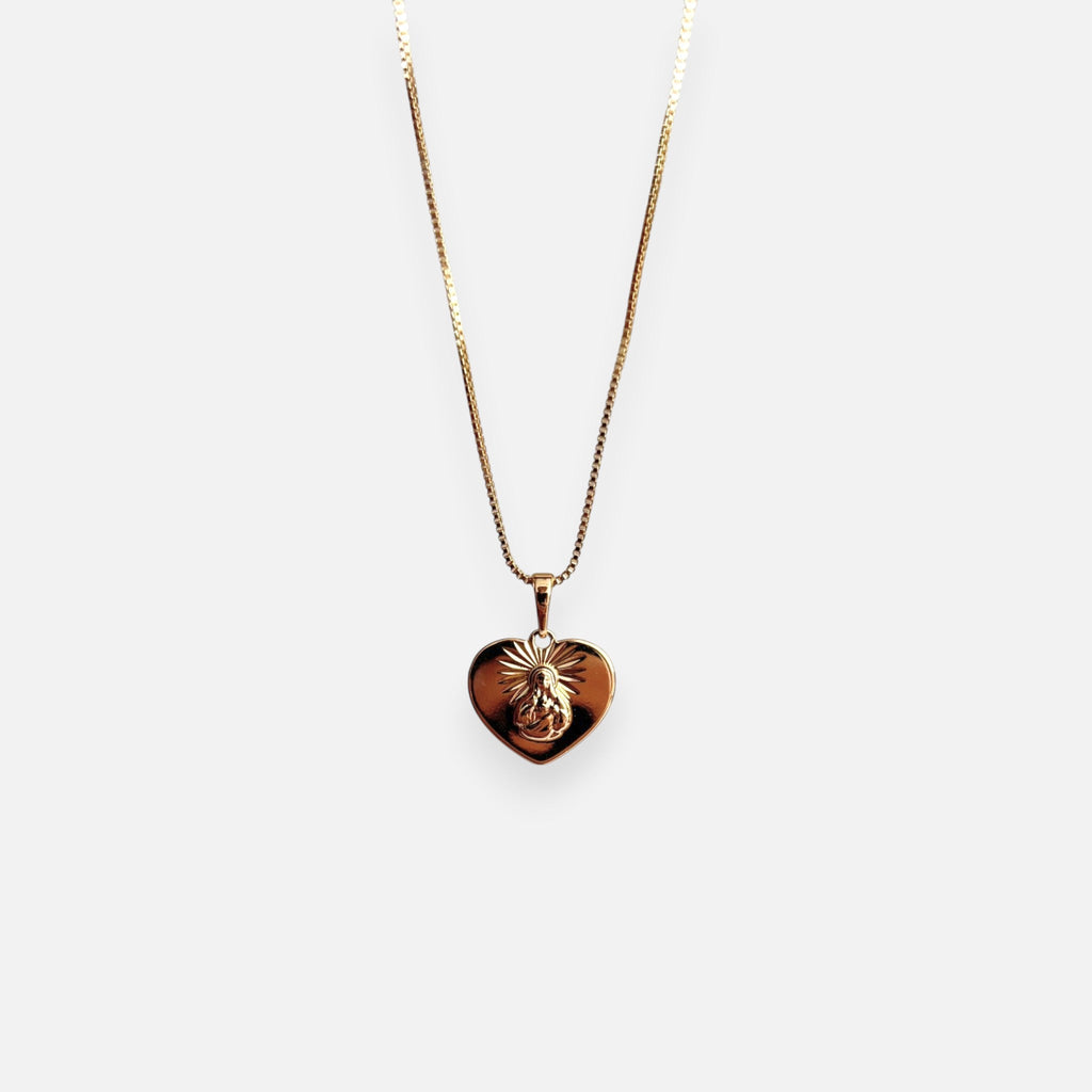 Cadena de tejido Veneciana en acabado dorado, acompañada por un dije en forma de corazón doble cara o reversible. Por una cara presenta la imagen del Sagrado Corazón de Jesús con halo radiante y por la otra la figura de la Virgen del Carmen sobre un fondo texturizado de destellos. Una pieza versátil de gran devoción y protección.