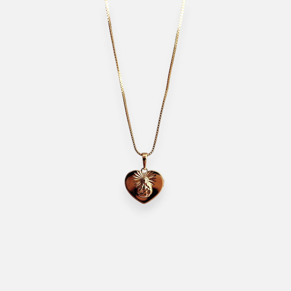 Cadena de tejido Veneciana en acabado dorado, acompañada por un dije en forma de corazón doble cara o reversible. Por una cara presenta la imagen del Sagrado Corazón de Jesús con halo radiante y por la otra la figura de la Virgen del Carmen sobre un fondo texturizado de destellos. Una pieza versátil de gran devoción y protección.