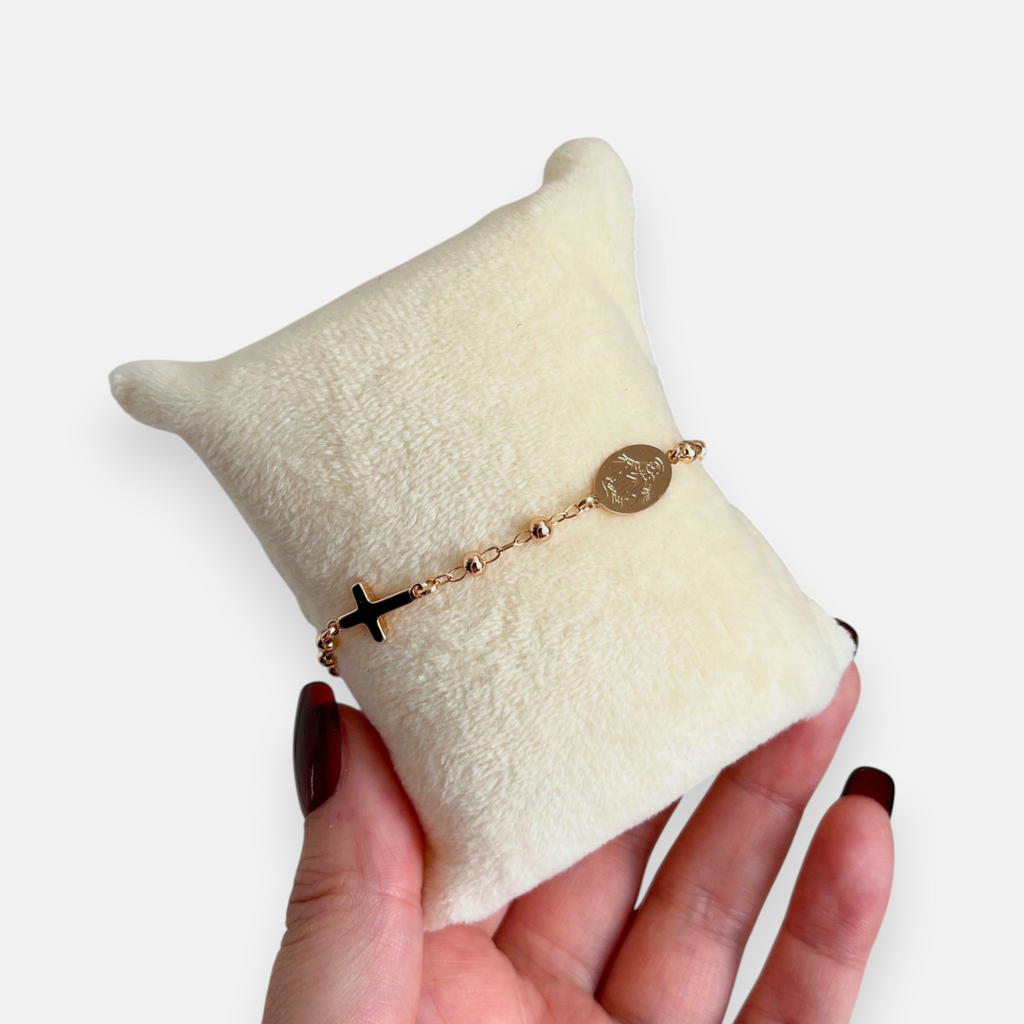 Pulsera tipo denario Hv Hermanas Villegas en oro rosé con cruz y medalla de la Virgen Milagrosa sobre cojín de terciopelo