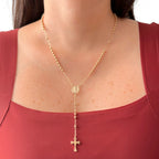 Rosario de estilo refinado en acabado dorado, elaborado con una fina cadena intercalada con esferas o balines pulidos. Presenta una medalla central ovalada con la figura en relieve de la Virgen Milagrosa y culmina en una delicada cruz colgante de contornos lisos. Una joya devocional de elegancia clásica y espiritualidad