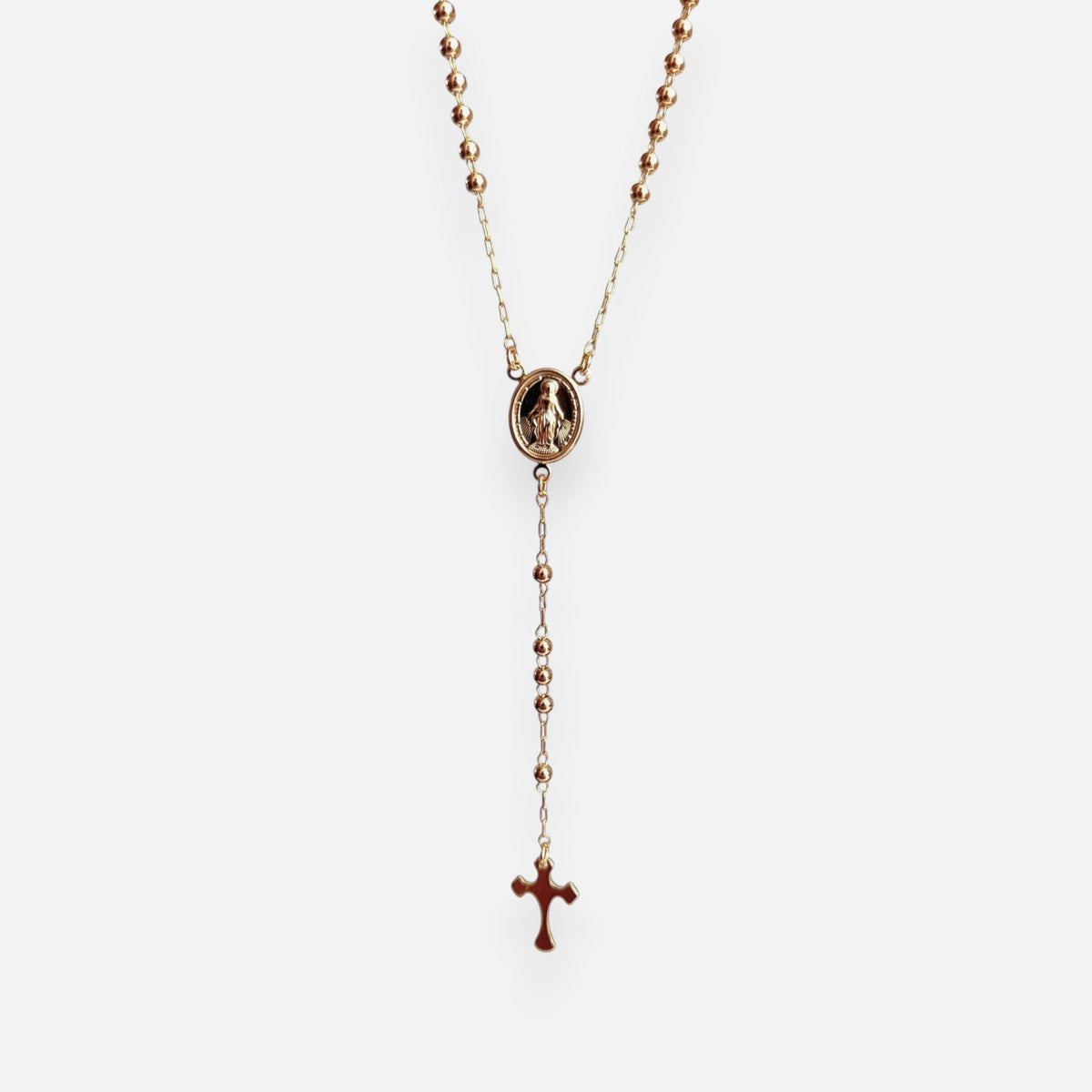 Rosario de estilo refinado en acabado dorado, elaborado con una fina cadena intercalada con esferas o balines pulidos. Presenta una medalla central ovalada con la figura en relieve de la Virgen Milagrosa y culmina en una delicada cruz colgante de contornos lisos. Una joya devocional de elegancia clásica y espiritualidad
