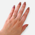 Anillo Hv Hermanas Villegas de oro rosé con dos cruces, circones brillantes y dije colgante en mano femenina