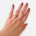 Anillo Hv Hermanas Villegas de doble banda en oro rosé con estrellas y circonia, diseño ajustable en mano femenina.