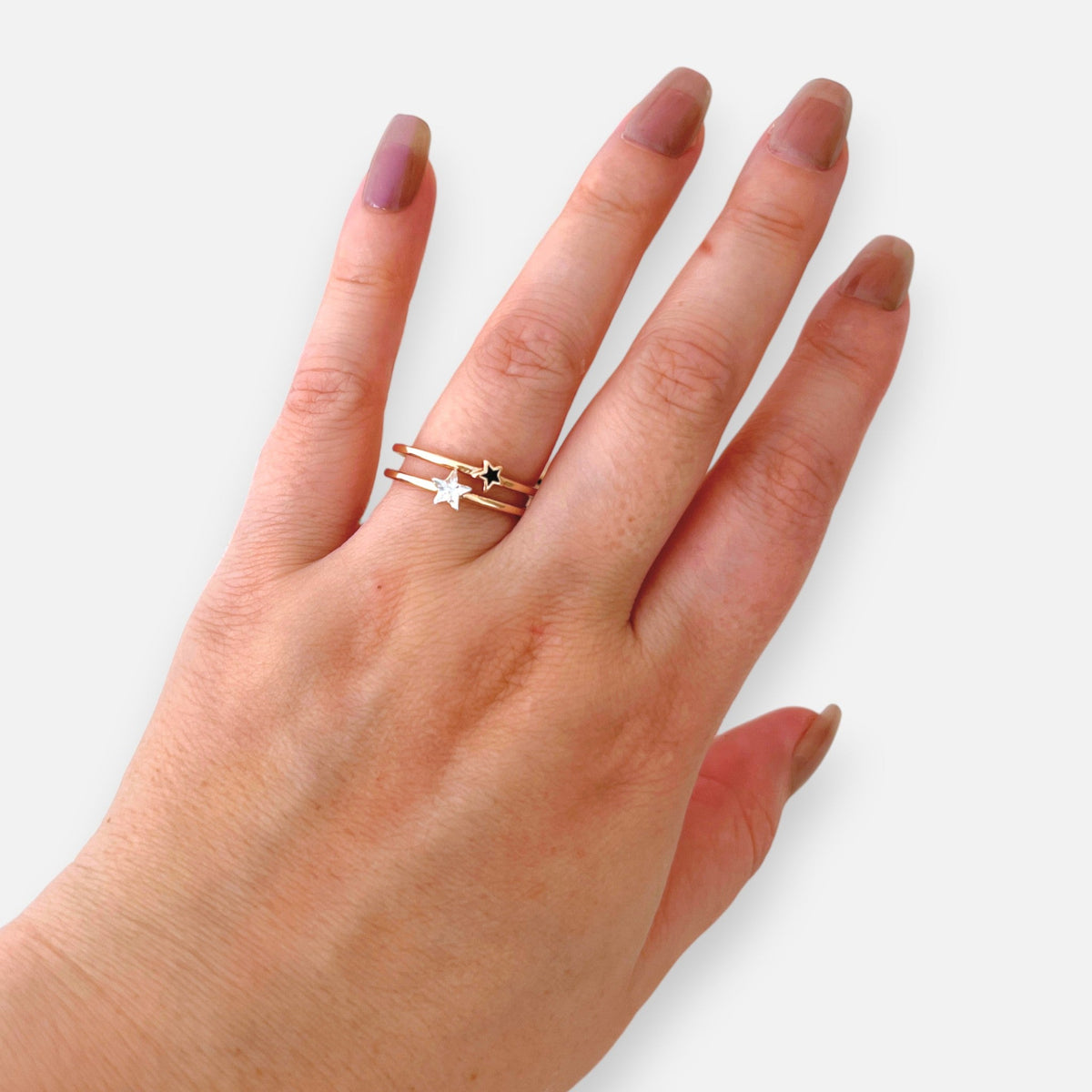 Anillo Hv Hermanas Villegas de doble banda en oro rosé con estrellas y circonia, diseño ajustable en mano femenina.