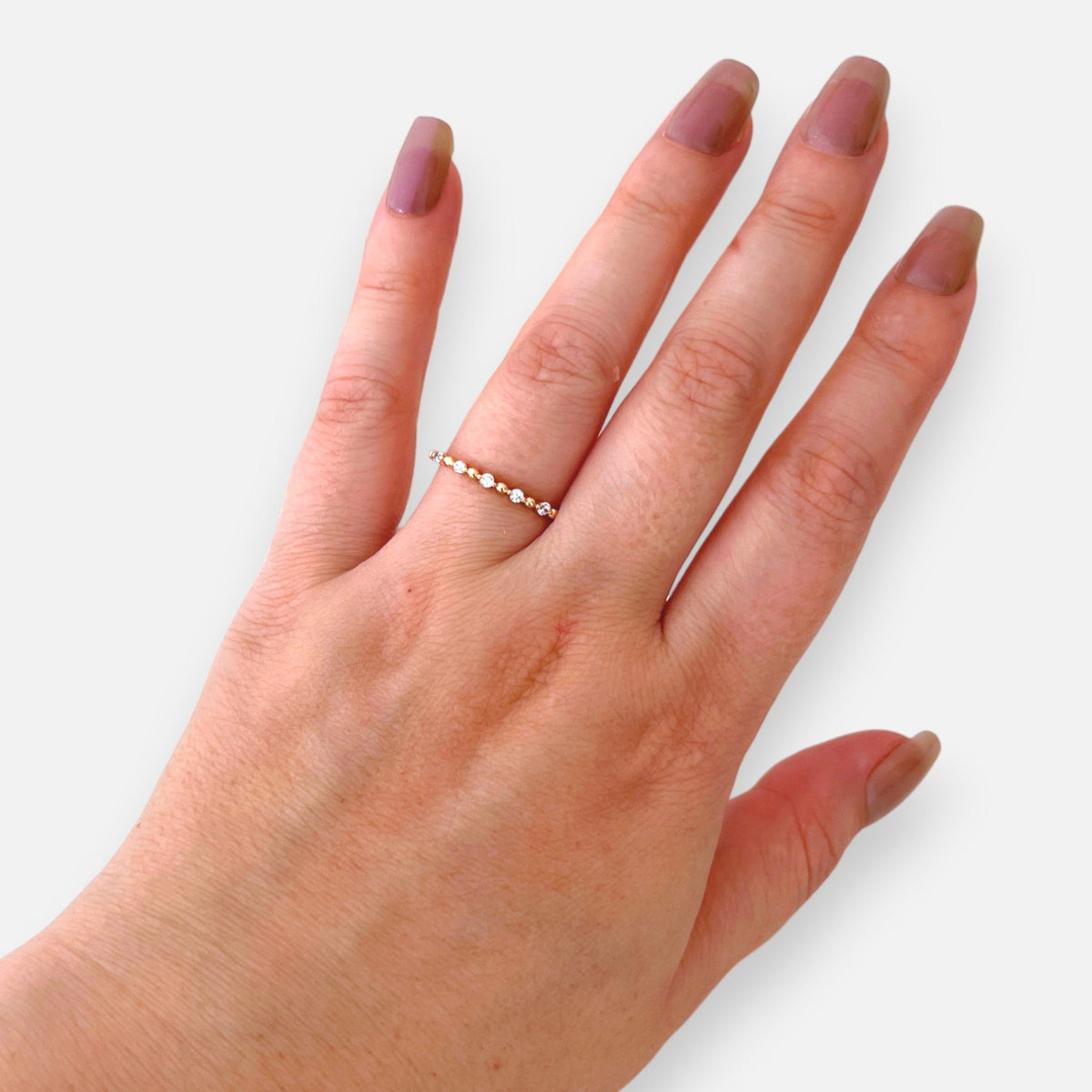 Anillo Hv Hermanas Villegas fino de oro rosé con circones y esferas metálicas en mano femenina