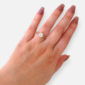 Anillo Hv Hermanas Villegas de compromiso en oro rosé con circonia central redonda y halo cuadrado en mano femenina.
