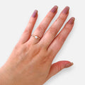 Anillo solitario Hv Hermanas Villegas en oro rosé con circonia central y banda de diseño infinito en mano femenina
