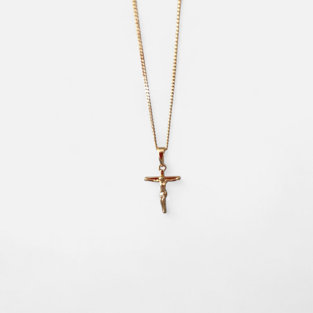 Collar Hv Hermanas Villegas con cadena grumet y dije de crucifijo estilizado en cobre con baño de oro rosé.