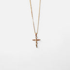 Collar Hv Hermanas Villegas con cadena grumet y dije de crucifijo estilizado en cobre con baño de oro rosé.