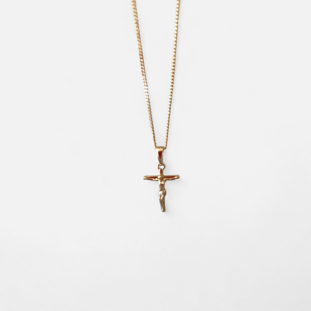 Collar Hv Hermanas Villegas con cadena grumet y dije de crucifijo estilizado en cobre con baño de oro rosé.