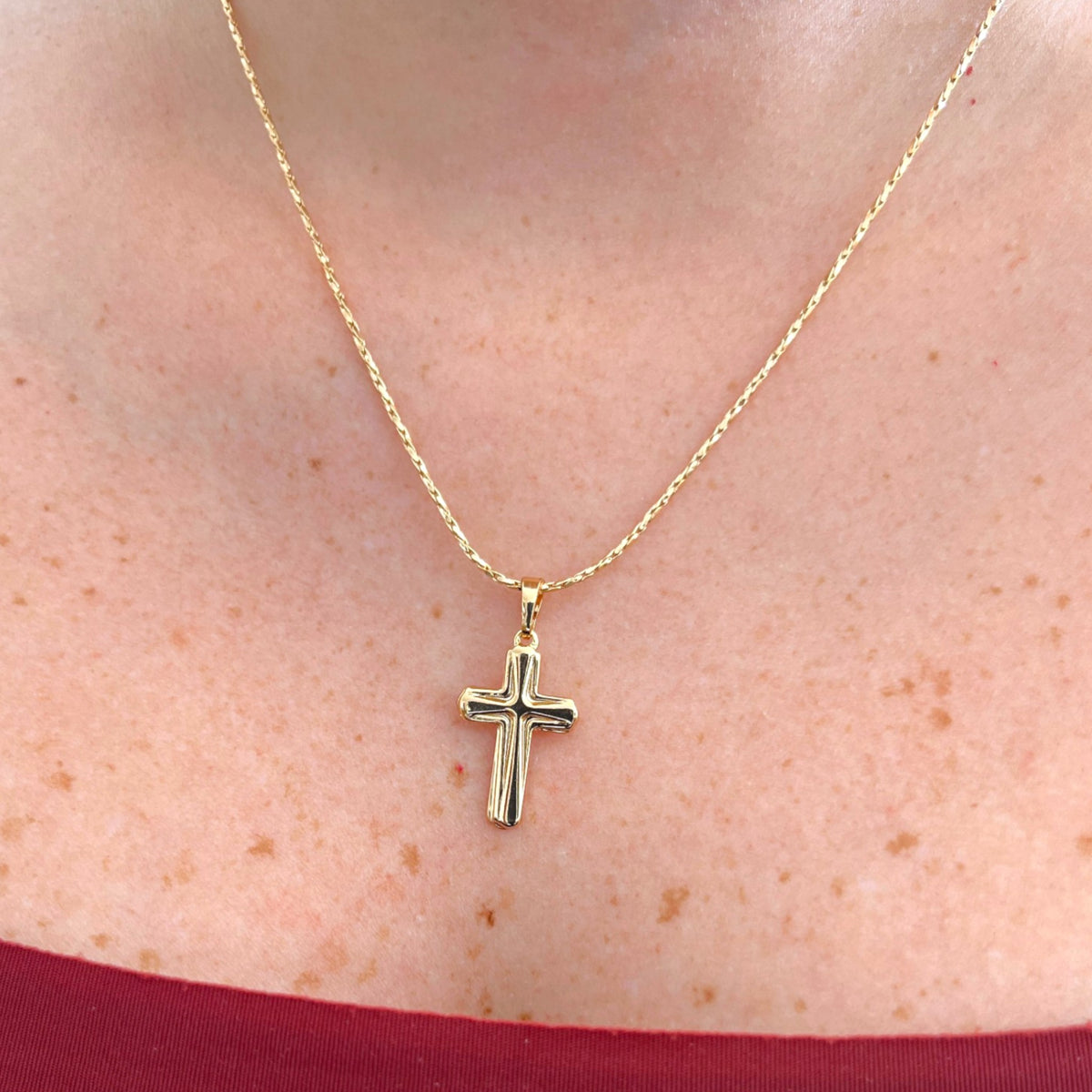 Cadena entorchada Hv Hermanas Villegas con dije de cruz clásica en baño de oro rosé sobre el cuello
