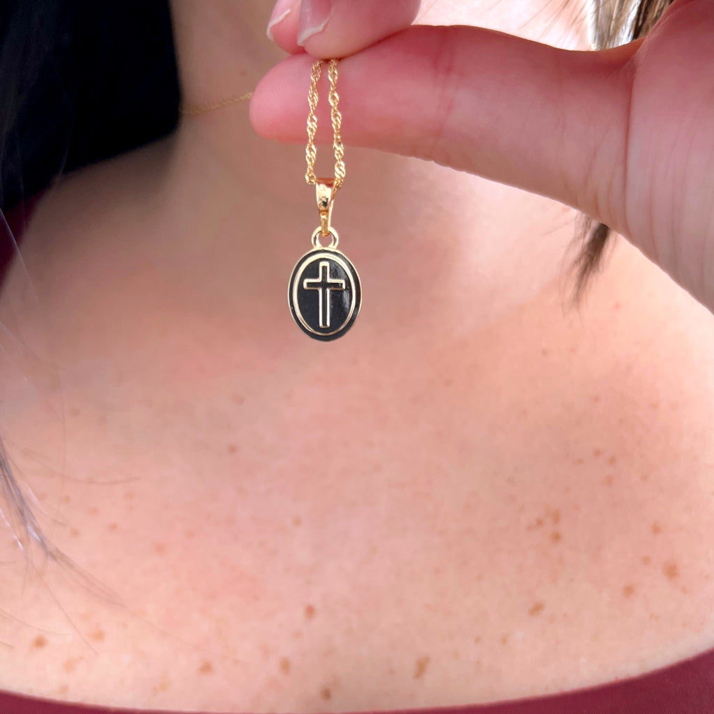 Cadena entorchada Hv Hermanas Villegas con medalla ovalada de cruz en tono dorado sobre el cuello de una mujer