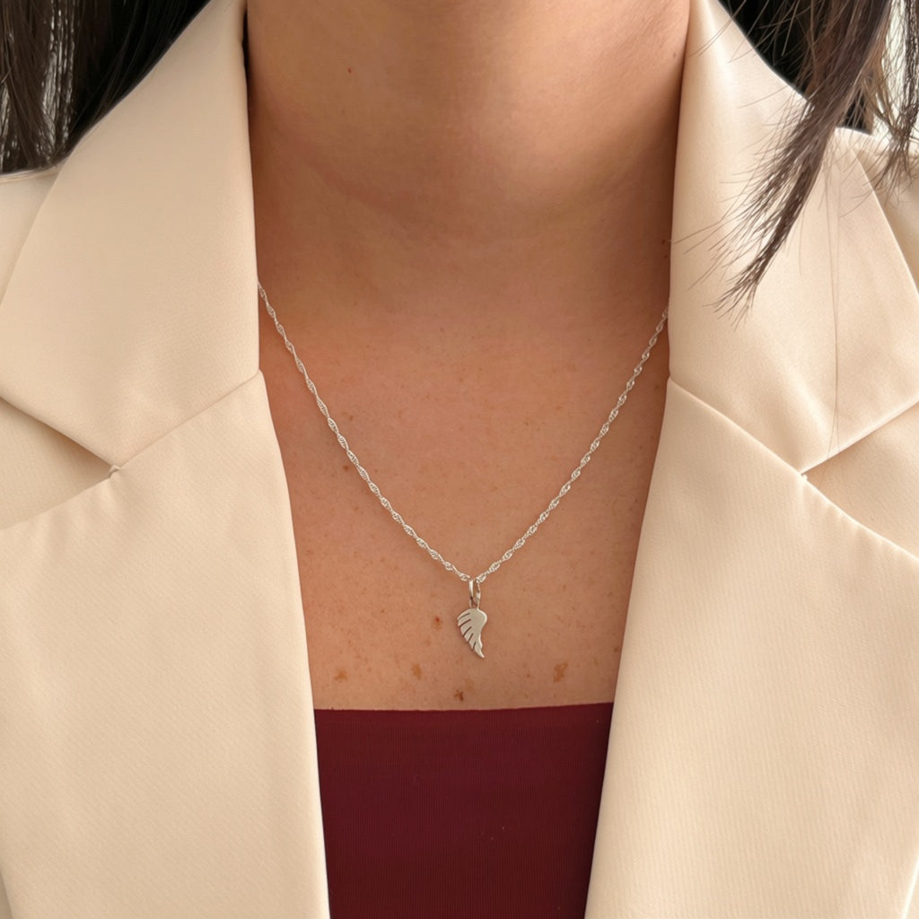 Collar Hv Hermanas Villegas de plata 925 con cadena tejido Singapur y dije de ala de ángel pulido sobre blazer beige