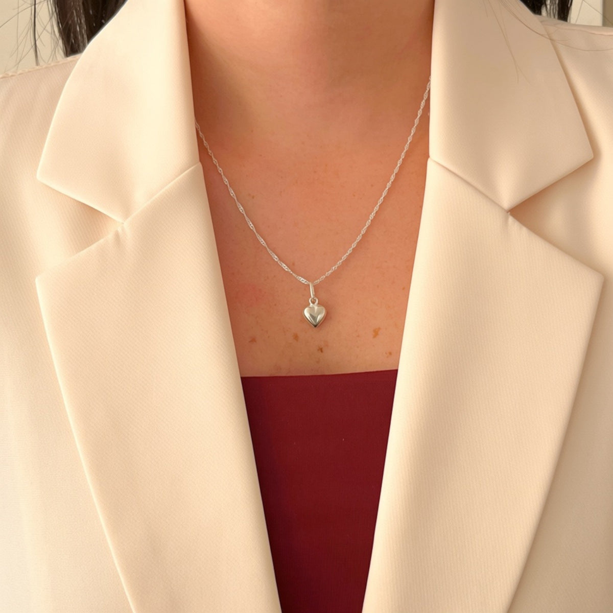 Cadena de plata 925 tejido Singapur con dije de corazón inflado pulido de Hv Hermanas Villegas sobre blazer crema
