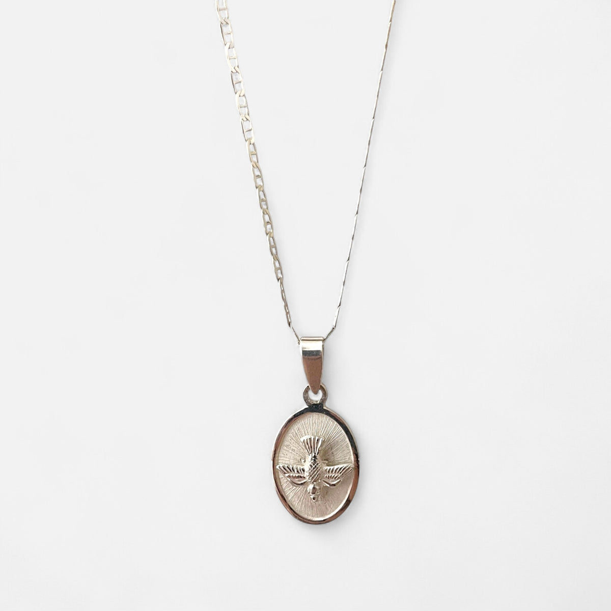 Collar Hv Hermanas Villegas de plata 925 con cadena Cartier y medalla ovalada del Espíritu Santo con fondo radiado.