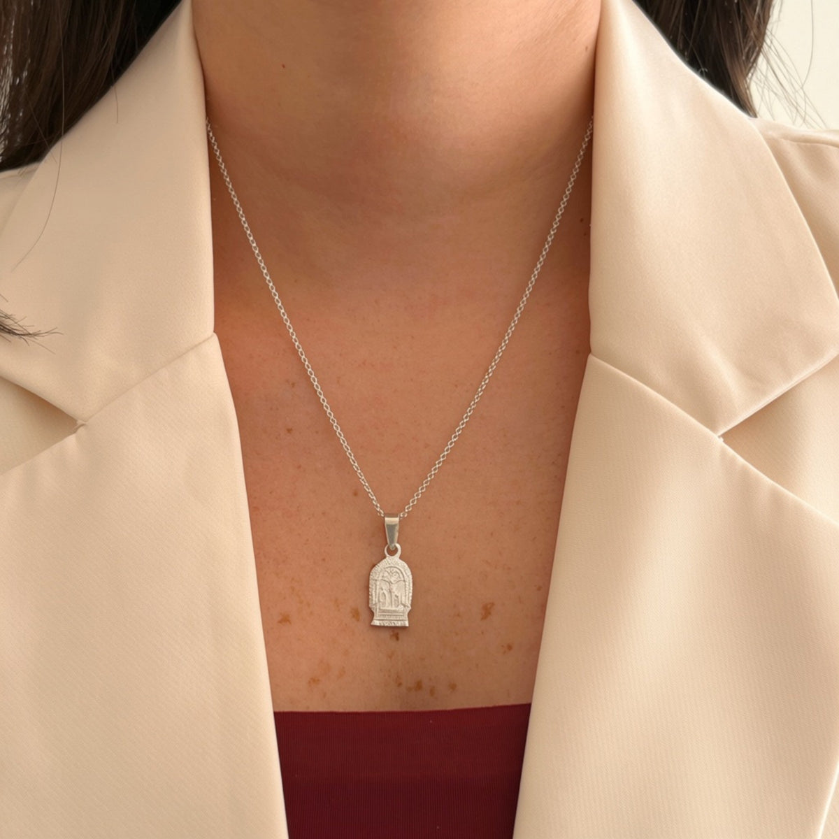 Cadena de plata 925 Hv Hermanas Villegas con medalla en relieve del Señor de los Milagros sobre blazer beige