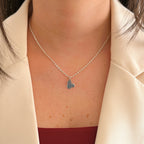 Cadena de plata 925 Hv Hermanas Villegas con dije de silueta de Minnie Mouse y tejido caracol sobre blazer crema