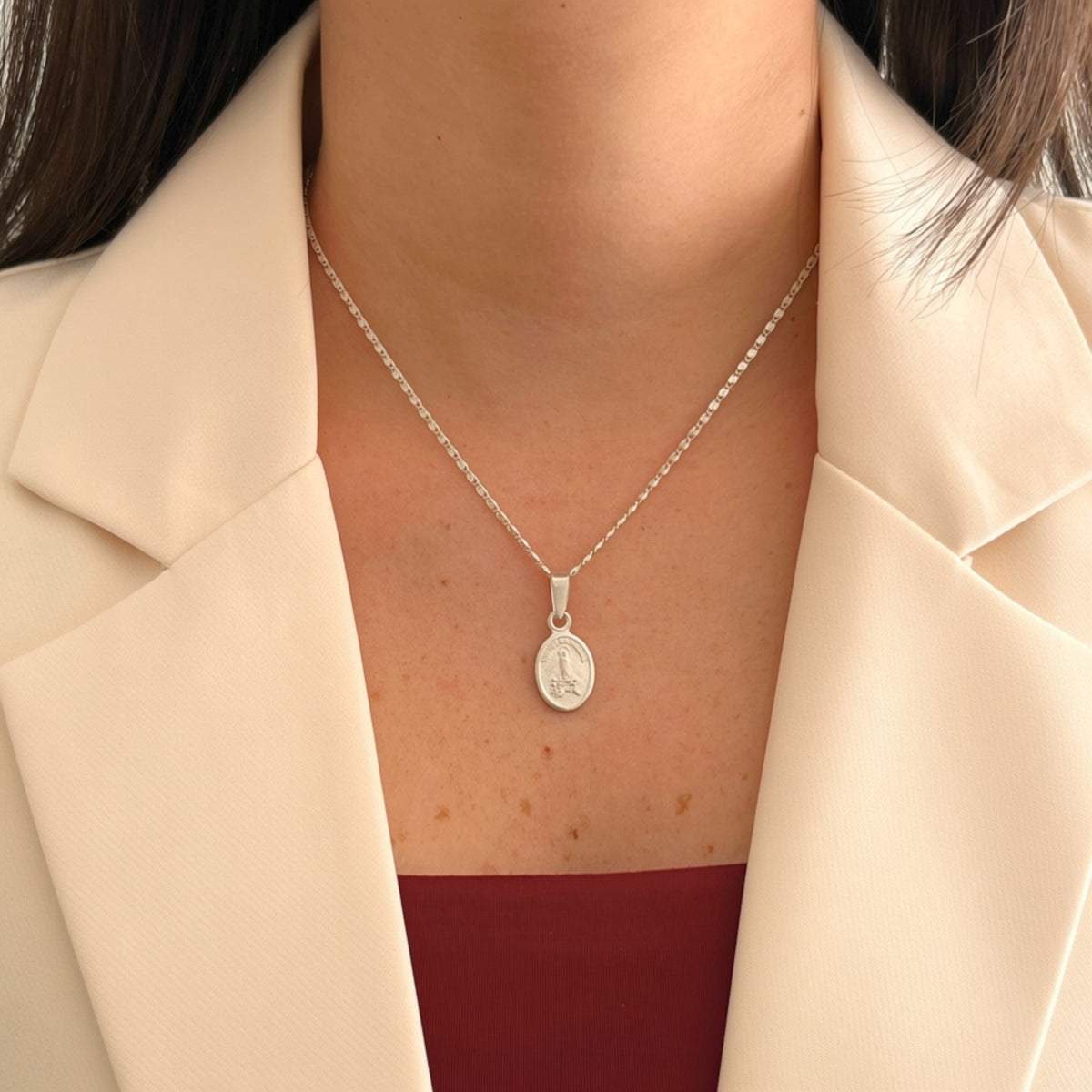 Cadena de plata 925 Hv Hermanas Villegas con medalla ovalada de la Virgen de Fátima sobre blazer beige