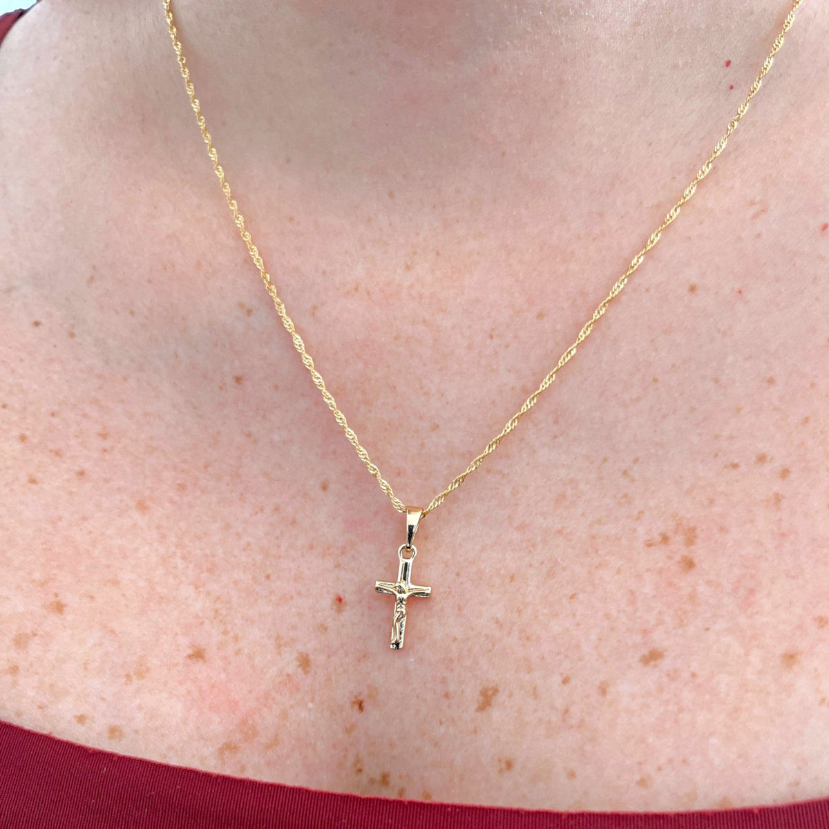 Cadena Singapur Hv Hermanas Villegas en cobre con baño de oro rosé y dije de crucifijo pulido sobre el cuello