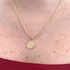 Collar Hv Hermanas Villegas con cadena veneciana y medalla de San Benito en oro rosé sobre el cuello de una mujer