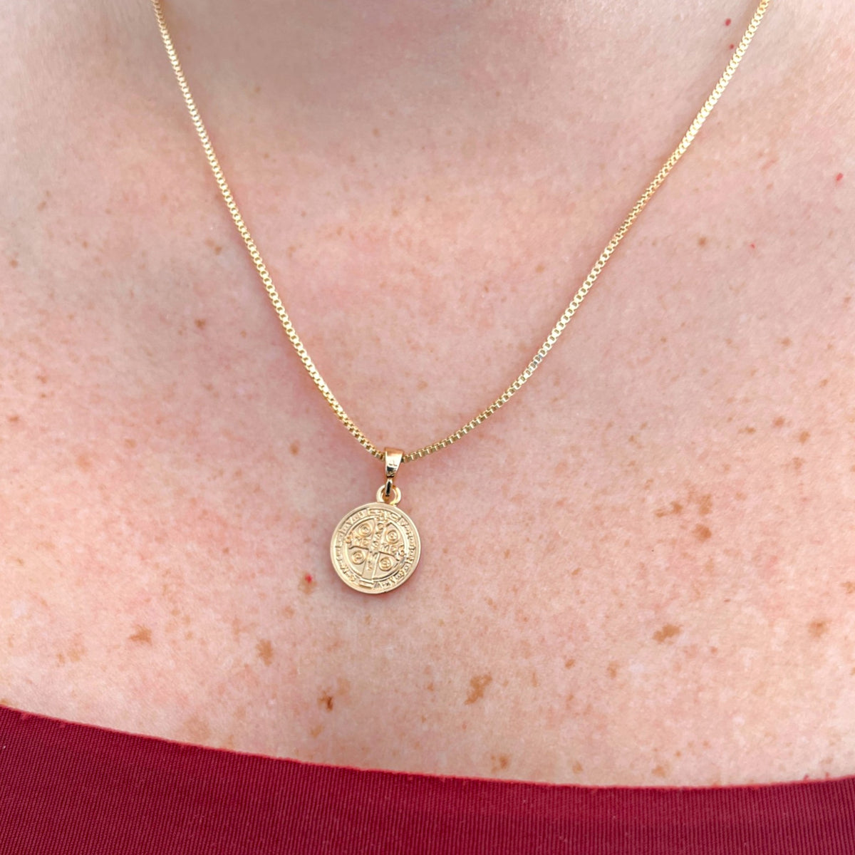 Collar Hv Hermanas Villegas con cadena veneciana y medalla de San Benito en oro rosé sobre el cuello de una mujer