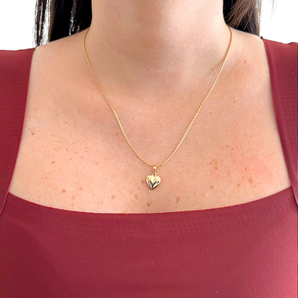 Collar Hv Hermanas Villegas con cadena anchor y dije de corazón inflado en baño de oro rosé sobre blusa granate