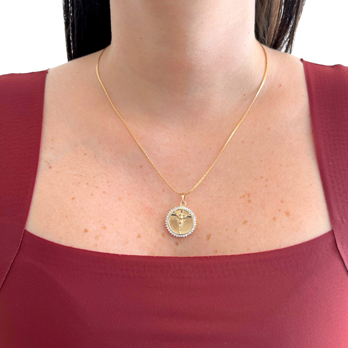 Collar Hv Hermanas Villegas con cadena anchor y medalla de Cristo en oro rosé con circonias sobre blusa granate
