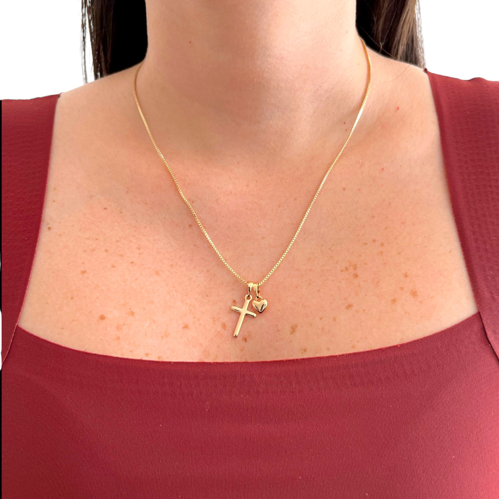 Collar Hv Hermanas Villegas de cadena veneciana en oro rosé con dijes de cruz y corazón sobre una blusa granate
