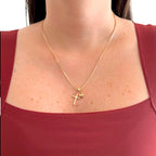 Collar Hv Hermanas Villegas de cadena veneciana en oro rosé con dijes de cruz y corazón sobre una blusa granate