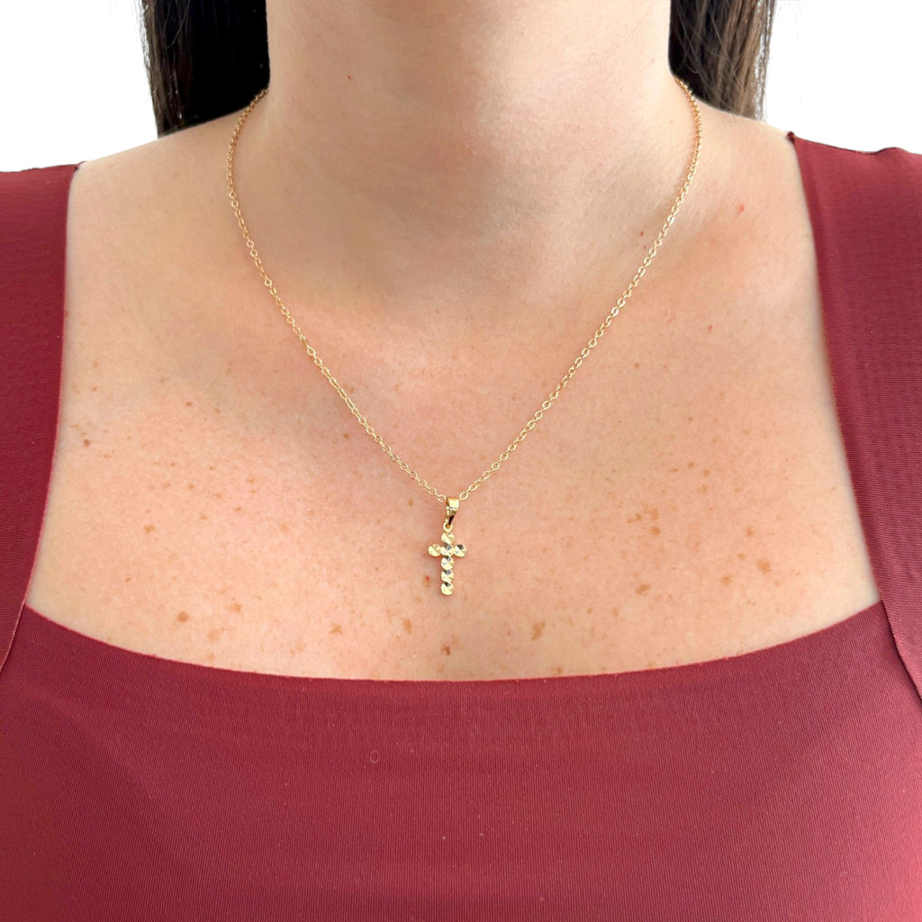 Collar Hv Hermanas Villegas de cadena forcet en baño de oro rosé con dije de cruz facetada brillante sobre blusa roja
