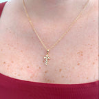Collar Hv Hermanas Villegas con cadena forcet y dije de cruz facetada en baño de oro rosé sobre cuello femenino.