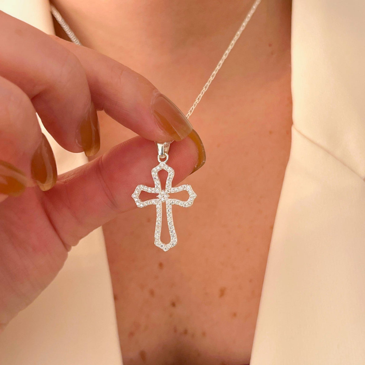 Collar Hv Hermanas Villegas de plata 925 con dije de cruz calada y circonias brillantes sobre una chaqueta clara