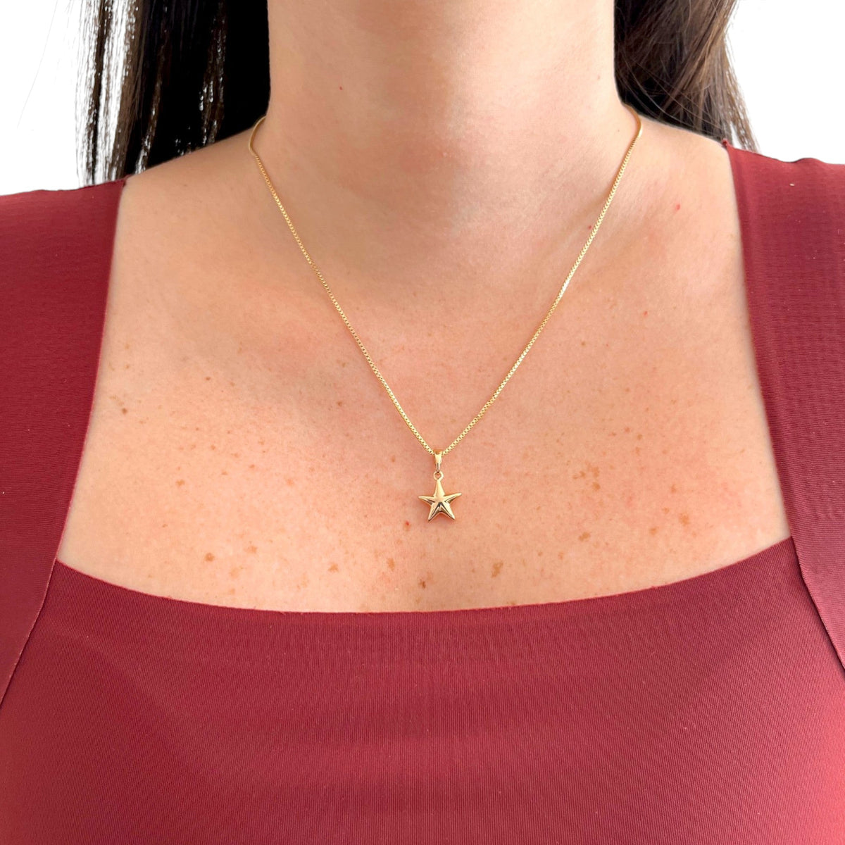 Collar Hv Hermanas Villegas con cadena veneciana y dije de estrella lisa en baño de oro rosé sobre blusa granate