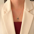 Collar Hv Hermanas Villegas de plata 925 con dije de corazón y turmalina negra sobre blazer color crema