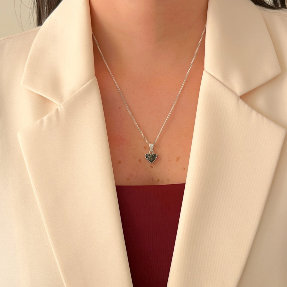 Collar Hv Hermanas Villegas de plata 925 con dije de corazón y turmalina negra sobre blazer color crema