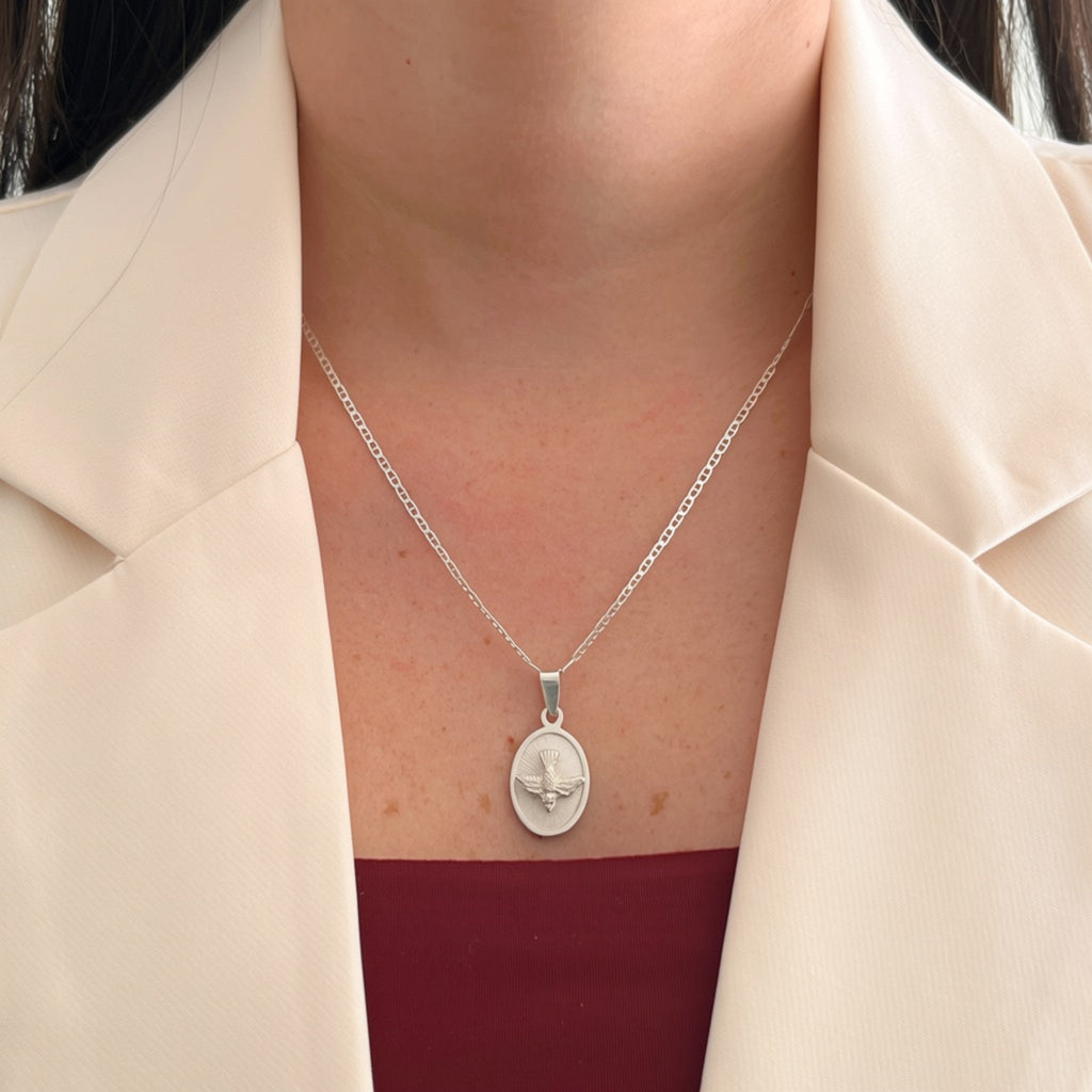 Collar Hv Hermanas Villegas de plata 925 con cadena Cartier y medalla ovalada del Espíritu Santo sobre blazer beige.