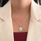Collar Hv Hermanas Villegas de plata 925 con cadena Cartier y medalla ovalada del Espíritu Santo sobre blazer beige.