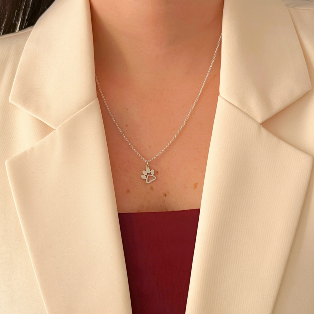 Collar Hv Hermanas Villegas de plata 925 con cadena forcet y dije de huellita de mascota sobre blazer color crema