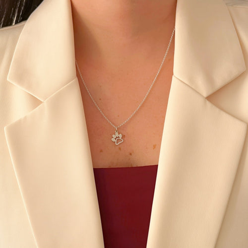 Collar Hv Hermanas Villegas de plata 925 con cadena forcet y dije de huellita de mascota sobre blazer color crema