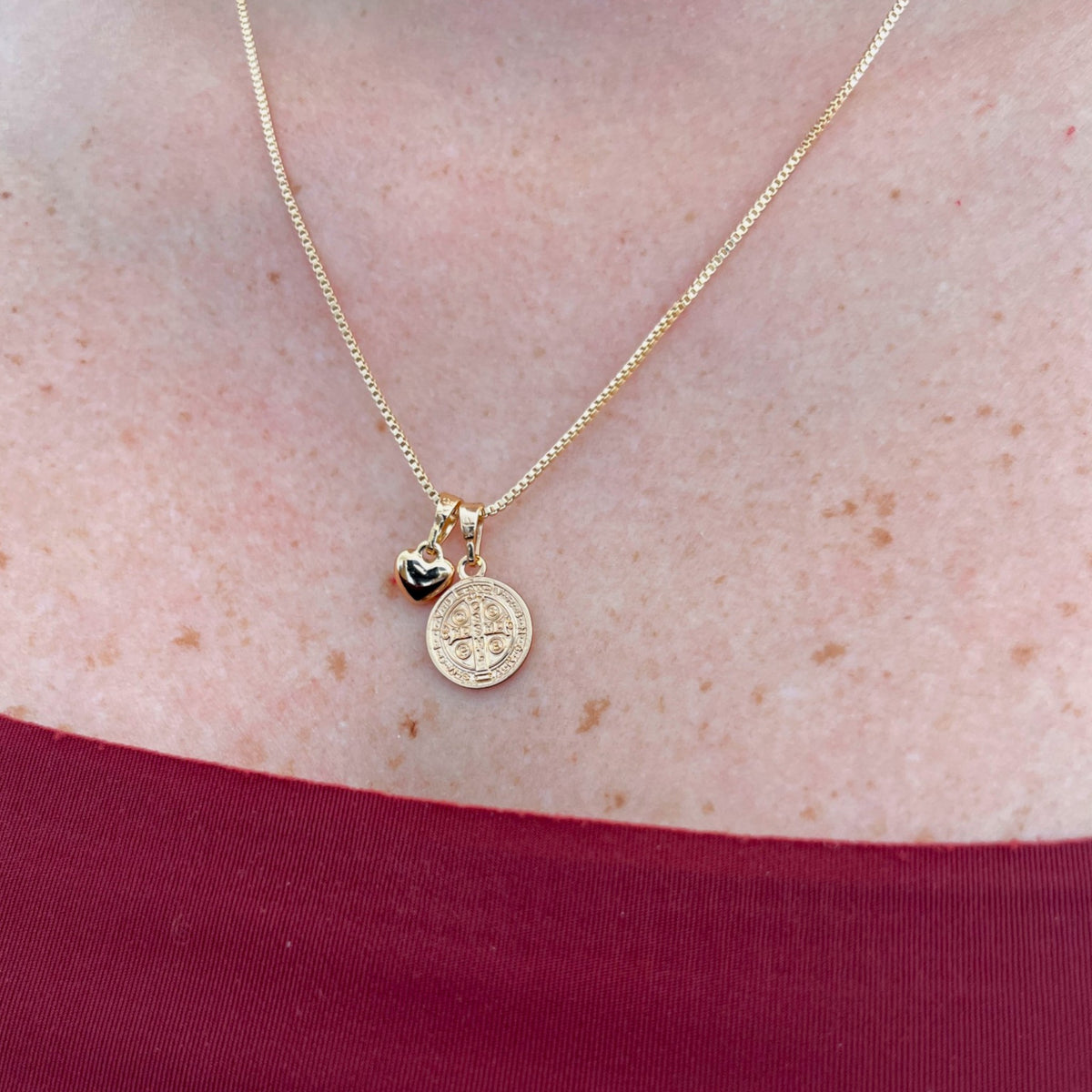 Collar Hv Hermanas Villegas con cadena veneciana, medalla de San Benito y dije de corazón en tono oro rosé.