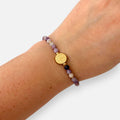 Pulsera Hv Hermanas Villegas de hilo con amatista facetada morada y medalla de San Benito en acero dorado