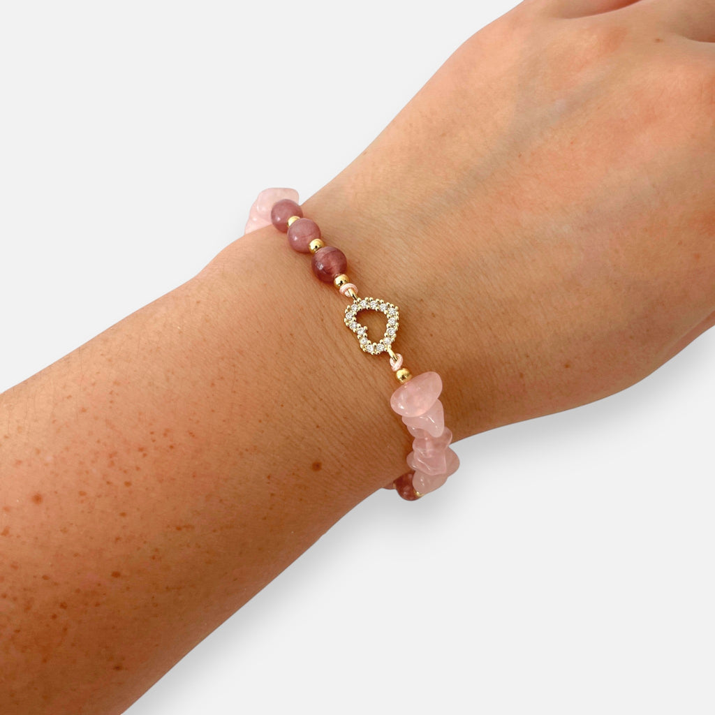Pulsera Hv Hermanas Villegas de cuarzo rosa con dije de corazón y circones en acero dorado sobre muñeca
